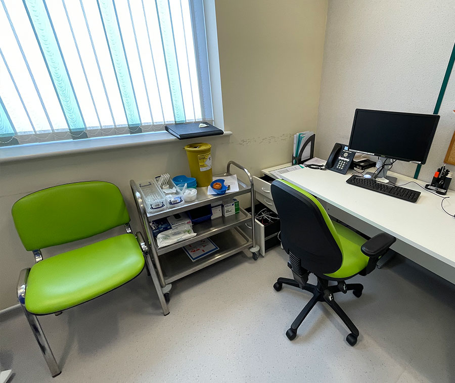 Interior of a hopsital room, featuring a chairs and equipment.